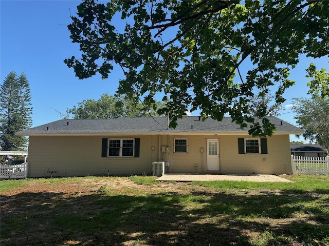 rear view of property featuring fence, cooling unit, a yard, a patio, and concrete block siding