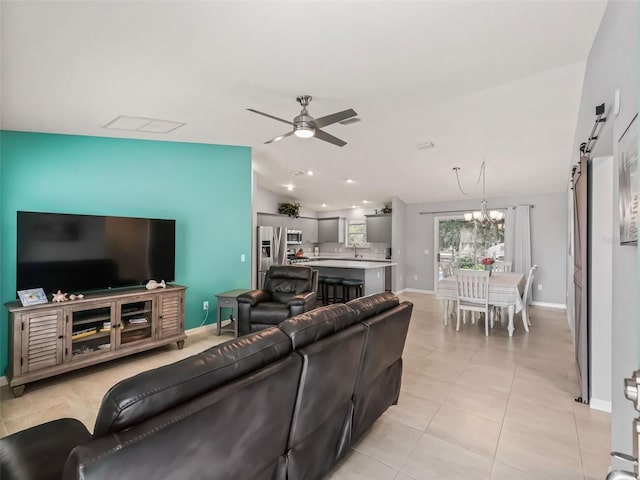 living area featuring lofted ceiling, baseboards, a barn door, ceiling fan with notable chandelier, and light tile patterned floors