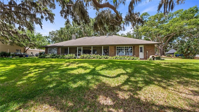 view of front of house with brick siding, a front lawn, and a chimney