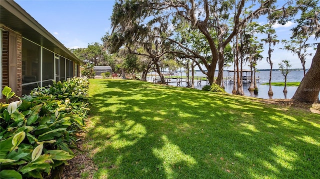 view of yard featuring a sunroom and a water view