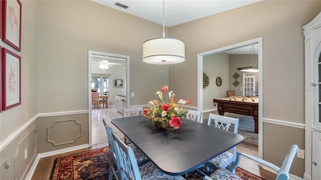 dining space with wainscoting, a ceiling fan, wood finished floors, and visible vents