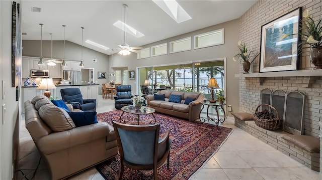 living room featuring a fireplace, high vaulted ceiling, a ceiling fan, light tile patterned floors, and a skylight