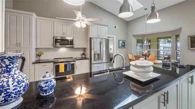 kitchen featuring decorative backsplash, pendant lighting, white cabinets, a sink, and appliances with stainless steel finishes