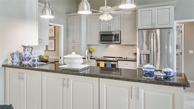 kitchen featuring hanging light fixtures, dark stone countertops, stainless steel appliances, a ceiling fan, and decorative backsplash