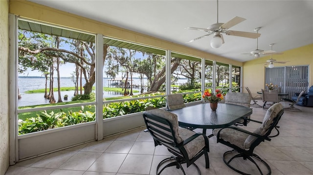 sunroom / solarium featuring a water view, ceiling fan, and outdoor dining space