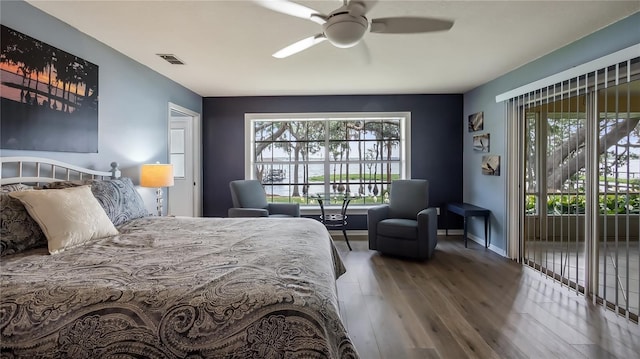 bedroom featuring baseboards, multiple windows, wood finished floors, and visible vents