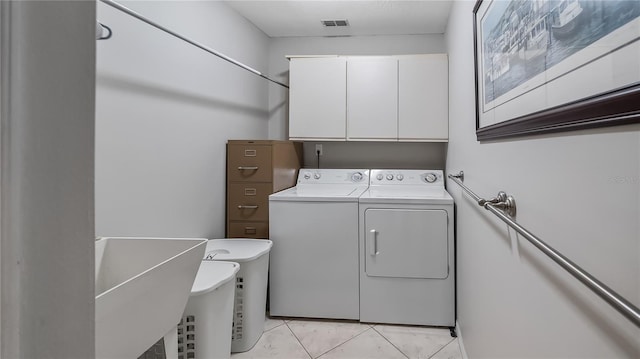 laundry room featuring visible vents, washing machine and dryer, cabinet space, a sink, and light tile patterned flooring