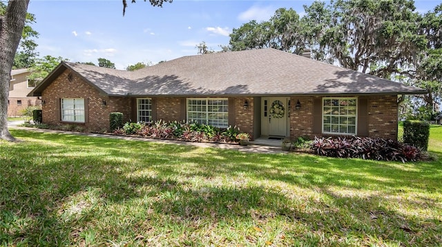 ranch-style house featuring brick siding, roof with shingles, and a front yard