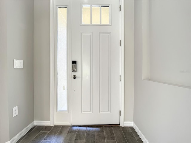 foyer featuring baseboards and dark wood-style flooring