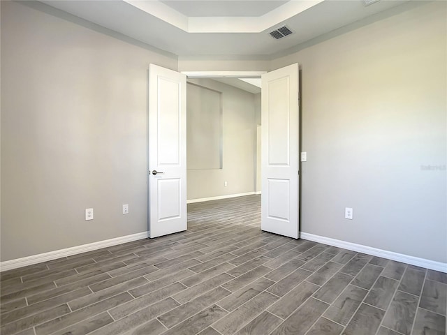 spare room with dark wood-style flooring, baseboards, and a raised ceiling