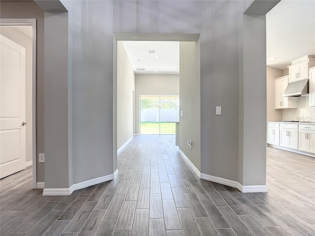 hall featuring wood tiled floors and baseboards
