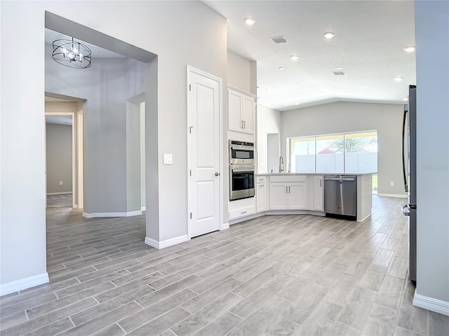 kitchen featuring stainless steel appliances, baseboards, white cabinetry, vaulted ceiling, and light wood-style flooring