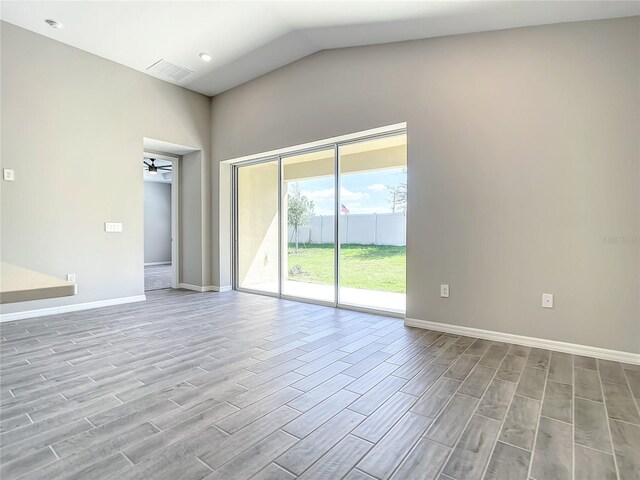 empty room with baseboards, wood finished floors, vaulted ceiling, and a ceiling fan