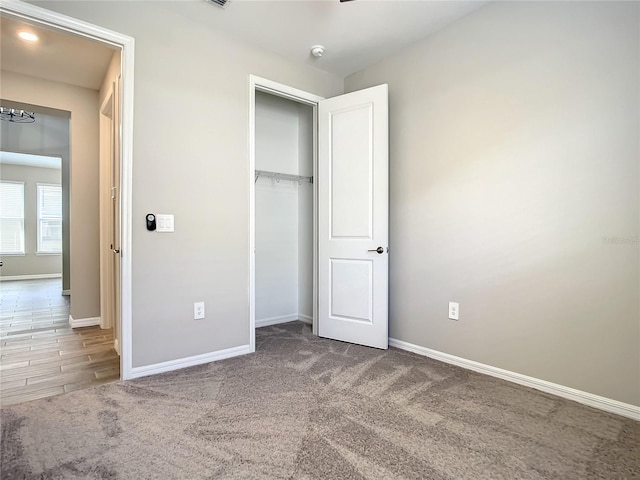 unfurnished bedroom featuring baseboards, carpet floors, and a closet