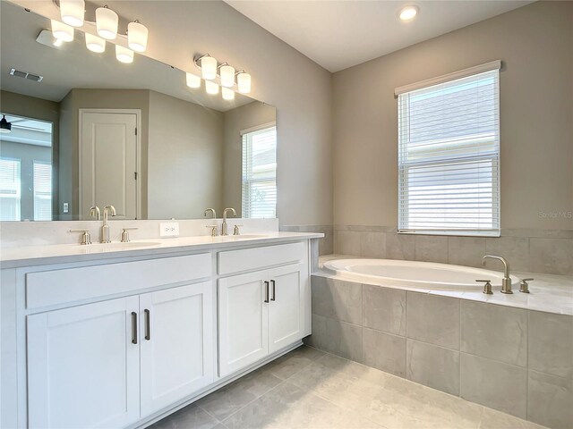full bathroom with tile patterned flooring, a bath, and double vanity