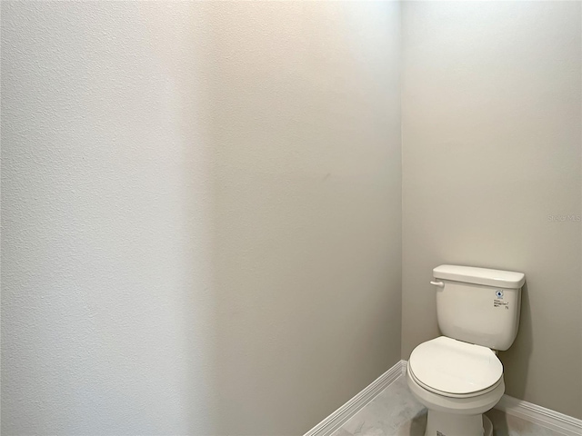 bathroom featuring baseboards and toilet