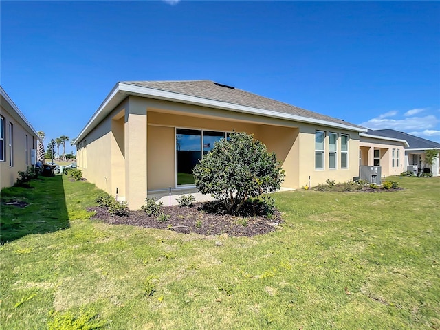 back of house featuring stucco siding and a yard