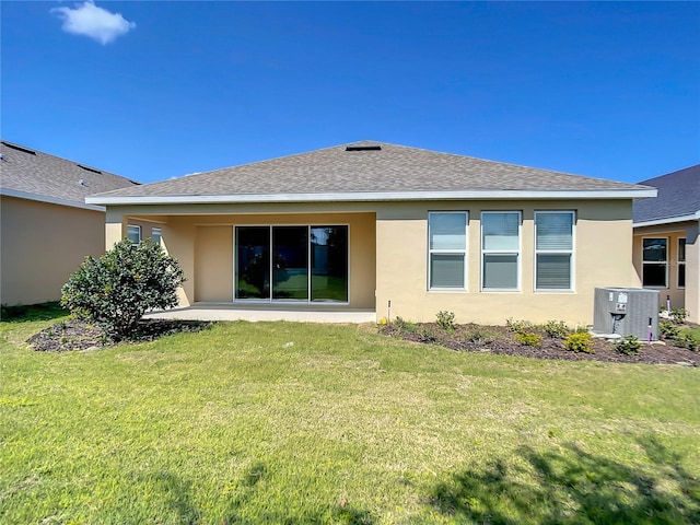 rear view of property featuring stucco siding, central AC unit, a shingled roof, and a lawn