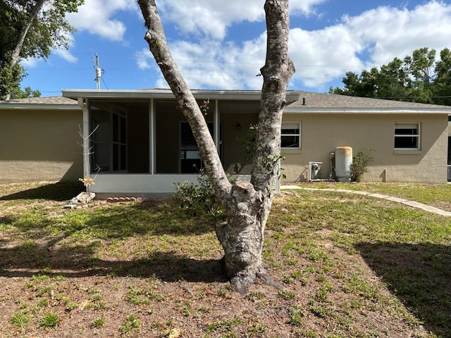 4046 E Bennett St, Inverness, FL 34453 - rear view of house featuring a sunroom, a lawn, and stucco siding