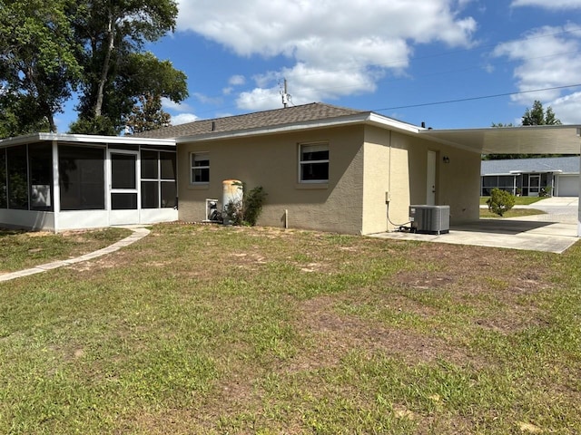 4046 E Bennett St, Inverness, FL 34453 - rear view of property with stucco siding, a sunroom, a lawn, a carport, and driveway