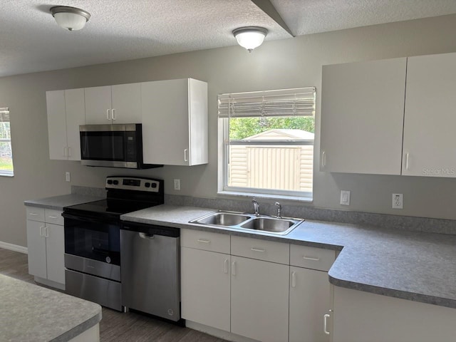 4046 E Bennett St, Inverness, FL 34453 - kitchen with a textured ceiling, appliances with stainless steel finishes, wood finished floors, a sink, and white cabinets