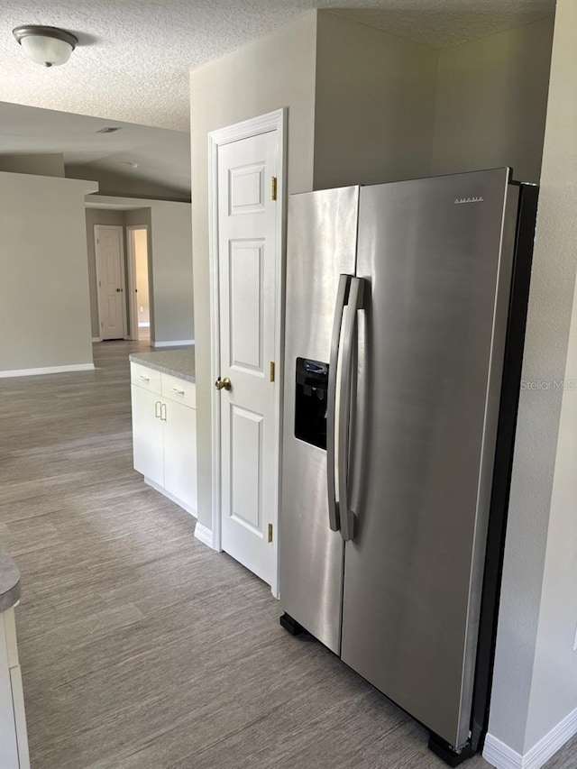 4046 E Bennett St, Inverness, FL 34453 - kitchen featuring white cabinets, stainless steel fridge, light countertops, baseboards, and vaulted ceiling