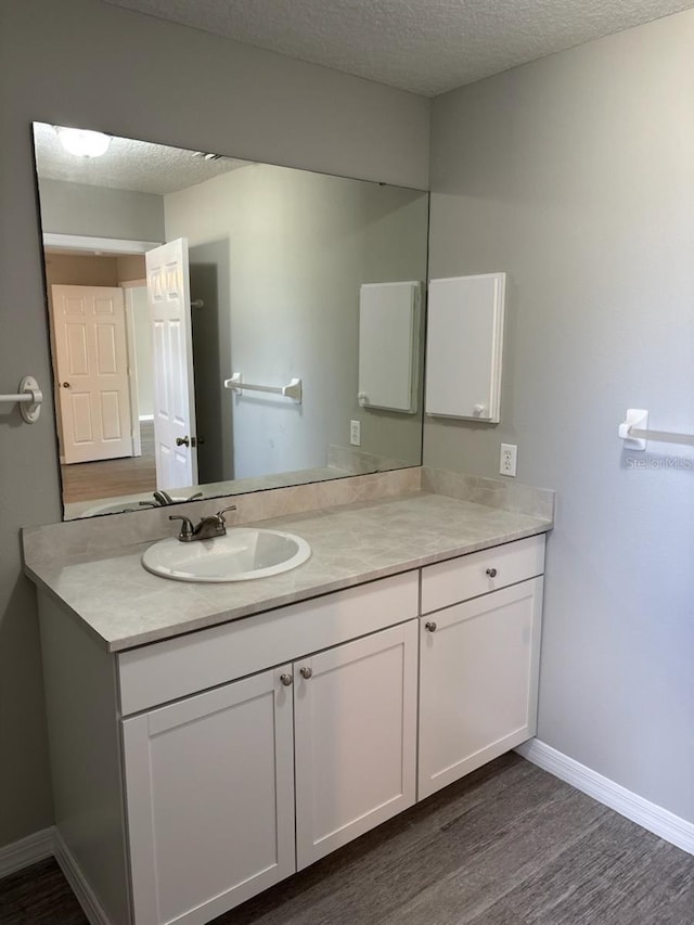 4046 E Bennett St, Inverness, FL 34453 - bathroom featuring vanity, baseboards, a textured ceiling, and wood finished floors