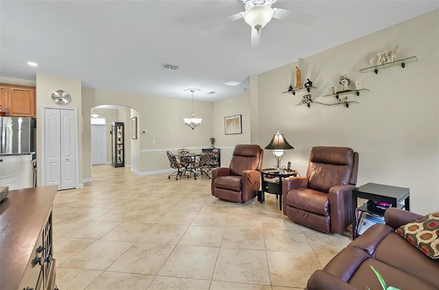 living room with baseboards, visible vents, light tile patterned flooring, ceiling fan with notable chandelier, and arched walkways