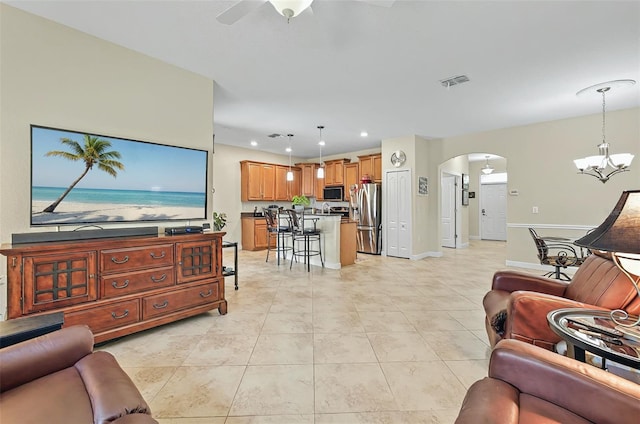 living room with ceiling fan with notable chandelier, visible vents, arched walkways, light tile patterned flooring, and recessed lighting
