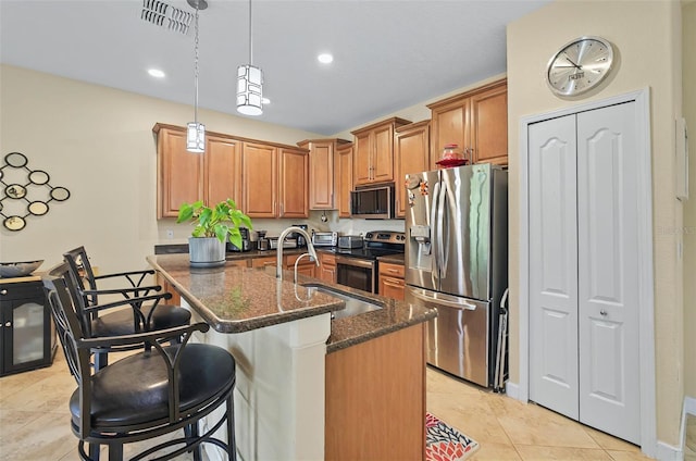 kitchen with light tile patterned floors, a sink, dark stone counters, stainless steel appliances, and visible vents