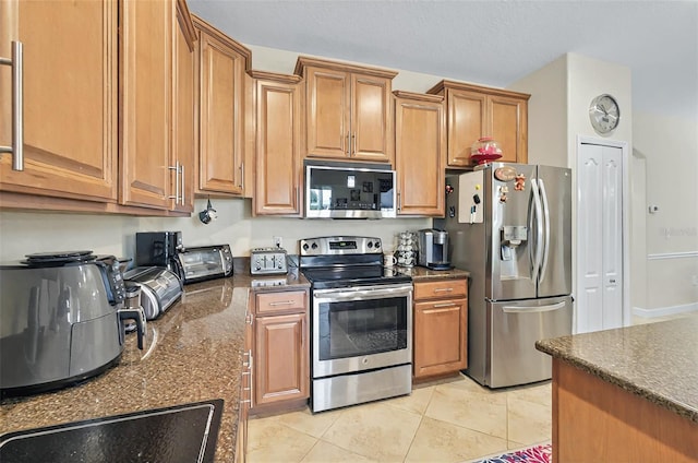 kitchen featuring brown cabinetry, stainless steel appliances, and light tile patterned flooring