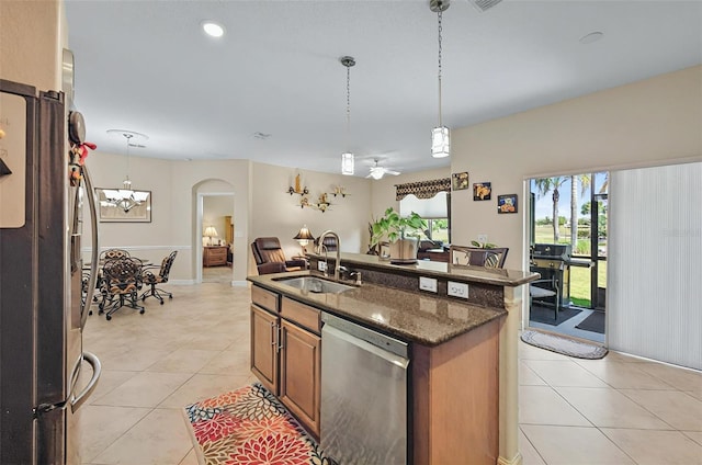 kitchen featuring a sink, stainless steel appliances, open floor plan, arched walkways, and light tile patterned floors