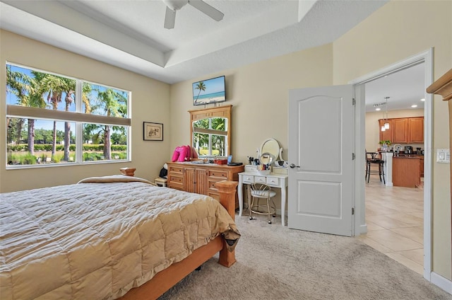 bedroom with light tile patterned floors, a raised ceiling, a ceiling fan, and light colored carpet