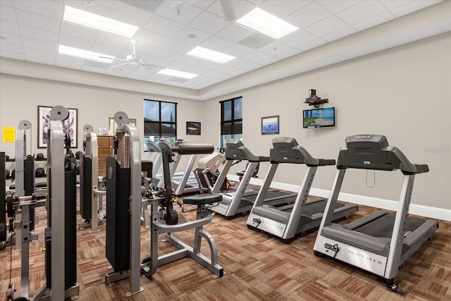 workout area with carpet flooring, baseboards, ceiling fan, and a paneled ceiling