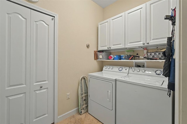 clothes washing area featuring baseboards, light tile patterned floors, cabinet space, and washer and clothes dryer