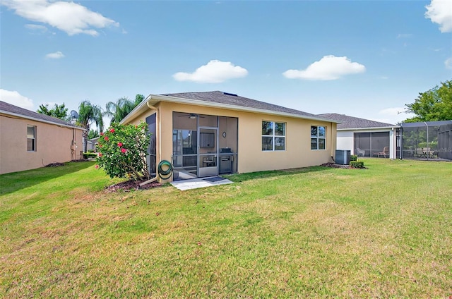 rear view of house featuring a lawn, central AC unit, stucco siding, and a sunroom