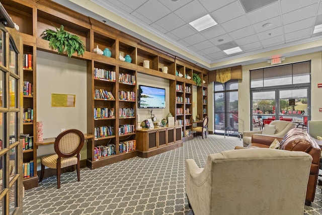 sitting room with ornamental molding, carpet flooring, bookshelves, and built in features