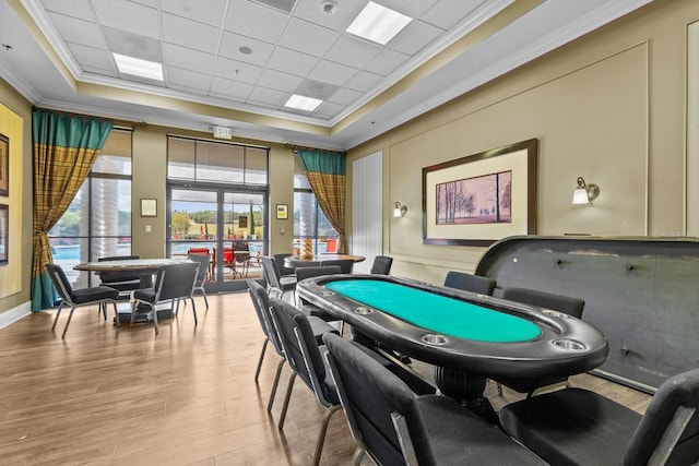 rec room with ornamental molding, a raised ceiling, and wood finished floors