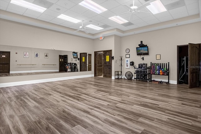 misc room with a paneled ceiling, ceiling fan, a towering ceiling, and wood finished floors