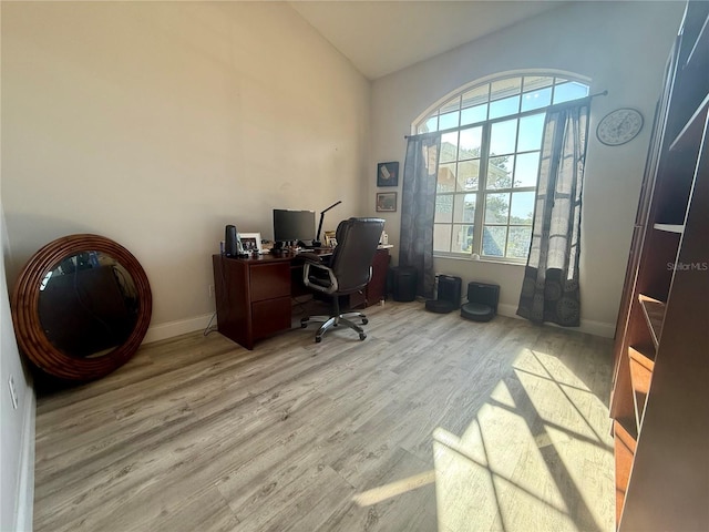 office area with wood finished floors, baseboards, and high vaulted ceiling