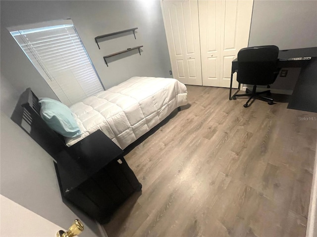 bedroom with wood finished floors and a closet