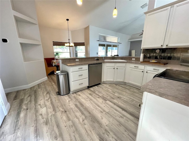 kitchen with stainless steel dishwasher, vaulted ceiling, a sink, a peninsula, and healthy amount of natural light