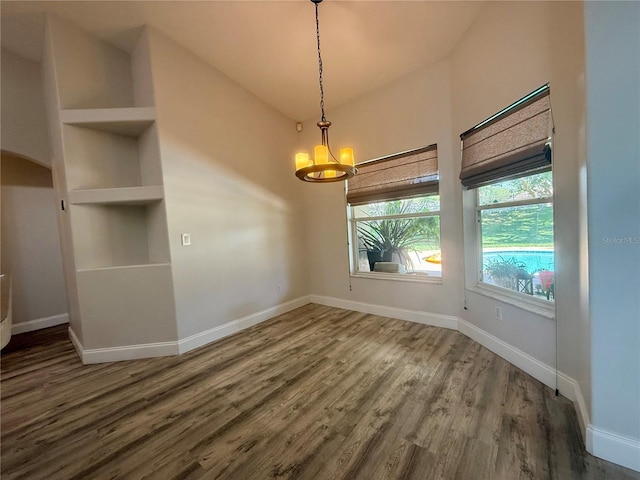 unfurnished dining area featuring wood finished floors, a chandelier, and baseboards