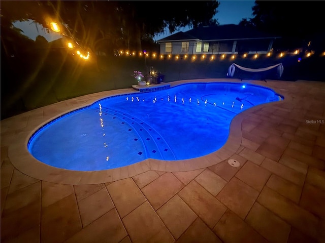 pool at twilight with a patio area