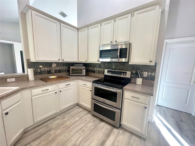 kitchen featuring stainless steel appliances, backsplash, light wood-type flooring, and light countertops