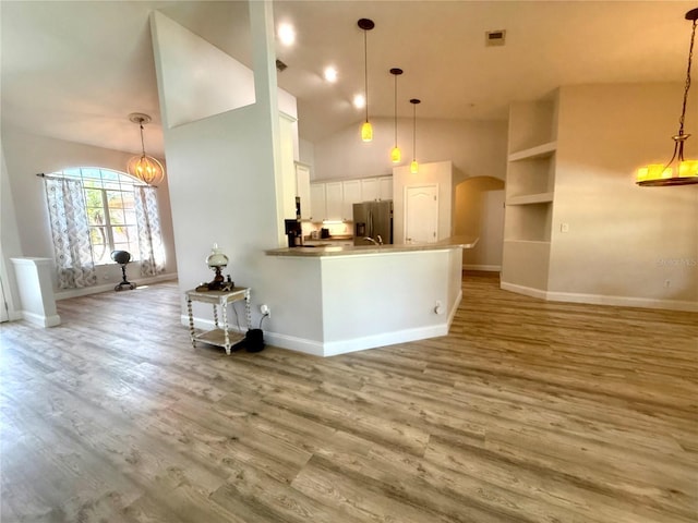 kitchen featuring stainless steel fridge with ice dispenser, arched walkways, white cabinets, wood finished floors, and baseboards