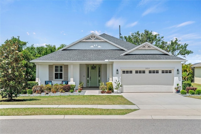 view of front of property with concrete driveway, a shingled roof, a front yard, and a garage