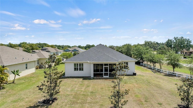 back of property with a lawn, fence, stucco siding, and a sunroom