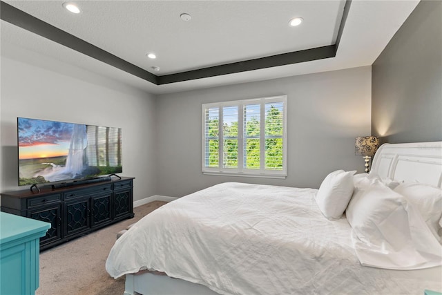 bedroom with baseboards, recessed lighting, a tray ceiling, and light carpet