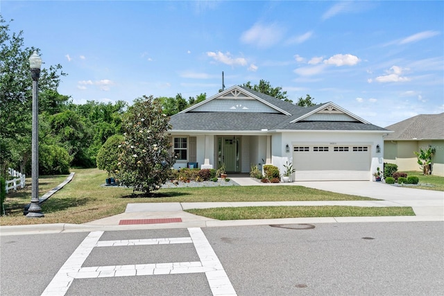 view of front of home featuring a shingled roof, an attached garage, a front lawn, stucco siding, and driveway